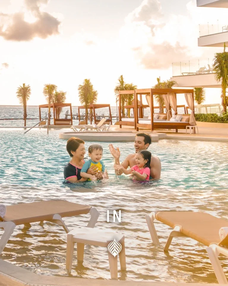 Family playing in outdoor pool with ocean view and tropical setting.