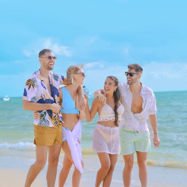 Group of young friends smiling and walking along the beach shore.